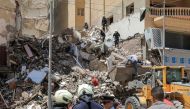 Civil defence first responders speak with a policeman (white) at the scene of a collapsed 13-storey-building in the Sidi Bishr district of Egypt's northern city of Alexandria on June 26, 2023. (Photo by Hazem GOUDA / AFP)