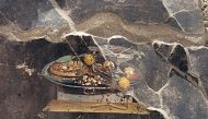 This handout photo taken and released on 25 June by Parco Archeologico di Pompei (Archaeological Park of Pompeii), shows a 2,000-year-old Pompeian painting, a still life, found by the new Regio IX excavations, depicted on the wall of an ancient Pompeian house that could be a distant ancestor of modern pizza. (Photo by Handout / Parco Archeologico di Pompei press office / AFP) 
