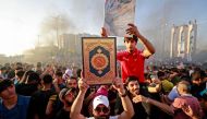 A supporter of Iraq's Sadrist movement holds up the Holy Quran outside the Swedish embassy in Baghdad on June 30, 2023. (Photo by Ahmad Al-Rubaye / AFP)