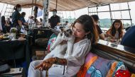 In this picture taken on August 13, 2023 a visitor sits with her cat on the Royal Albatross, a luxury tall ship that hosts sailing and dining experiences around the waters of Singapore with pets allowed. Photo by Roslan RAHMAN / AFP