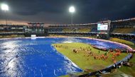 Ground staff cover the pitch after rain stopped play during the Asia Cup 2023 super four one-day international (ODI) cricket match between India and Pakistan at the R. Premadasa Stadium in Colombo on September 10, 2023. (Photo by Farooq Naeem / AFP)