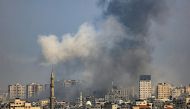 A plume of smoke rises above buildings in Gaza City during an Israeli air strike, on October 8, 2023. (Photo by Mahmud Hams / AFP)