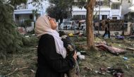 A woman reacts while holding a pillow as she stands amidst debris outside the site of the Ahli Arab hospital in central Gaza on October 18, 2023 in the aftermath of an overnight blast there. (Photo by Mahmud Hams / AFP)