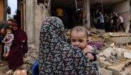 Women carry children as others check the damage in the aftermath of Israeli bombing in Rafah in the southern Gaza Strip on October 29, 2023. (Photo by Mohammed Abed / AFP)