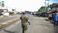 A soldier with the Sierra Leonean military police greets a man along an empty road in Freetown on November 26, 2023. (Photo by Saidu Bah / AFP)
 