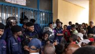 Congolese police officers block an entry after voters forced their way into a voting station in Kinshasa on December 20, 2023. (Photo by JOHN WESSELS / AFP)