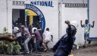 A Police officer throws a rock as opposition supporters run into a opposition leader Martin Fayulu's party house during a demonstration in Kinshasa on December 27, 2023. (Photo by JOHN WESSELS / AFP)
