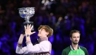 Italy's Jannik Sinner (L) celebrates with the Norman Brookes Challenge Cup trophy after defeating Russia's Daniil Medvedev in the men's singles final match on day 15 of the Australian Open tennis tournament in Melbourne on January 28, 2024. (Photo by David Gray / AFP)