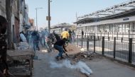 Protestors run away as a smoke grenade lands near them during clashes with police in Dakar on February 9, 2024. (Photo by GUY PETERSON / AFP)
