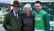 Trainer Willie Mullins (L) poses for a photograph with his wife Jackie and his son jockey Patrick Mullins, after his 100th win with Jasmin De Vaux winning the Champion Bumper race on the second day of the Cheltenham Festival at Cheltenham Racecourse, in Cheltenham, western England on March 13, 2024. (Photo by Ben Stansall / AFP)
