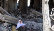 A Palestinian woman sits amid the rubble of a building in the Jabalia refugee camp in the northern gaza Strip, as she returned briefly with people who sought to check on their homes on May 31, 2024 (Photo by Omar AL-QATTAA / AFP)