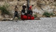 A worker loads dead fish on a continer attached to a mobile crane to remove dead fish floating from the Xiria River near Volos, central Greece, on August 28, 2024.  (Photo by Sakis MITROLIDIS / AFP)
