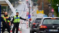 A German police officer flags down a car while controlling the traffic flow from Poland across the 