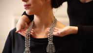 A gallery assistant poses wearing an 18th century diamond jewel necklace weighing approximately 300 carats at a press preview at Sotheby's in London on September 23, 2024. (Photo by Henry Nicholls / AFP)