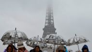 Visitors shelter from the rain with umbrellas on the Parvis des Droits de l'Homme on Esplanade du Tocadero across from the Eiffel Tower, as remnants of hurricane Kirk cause heavy rainfall over Paris, on October 9, 2024. (Photo by Ludovic MARIN / AFP)