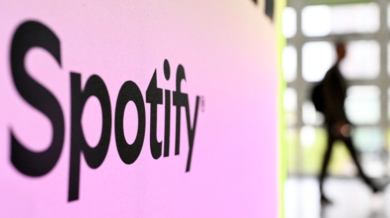 A person walks past a banner with an Spotify logo at the Frankfurt book fair on October 17, 2024. Photo by Kirill KUDRYAVTSEV / AFP