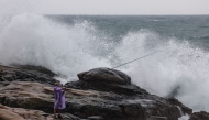 A fisherman holds a fishing rod next to waves as Typhoon Kong-rey approaches, in Keelung on October 29, 2024. (Photo by I-Hwa CHENG / AFP)