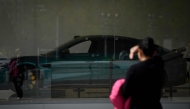 A woman looks at an electric car showroom in Beijing on April 4, 2025. (Photo by WANG Zhao / AFP)