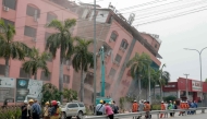 Rescue workers stand on the street next to a collapsed building in Mandalay on April 5, 2025, following the March 28 earthquake. (Photo by Zaw Htun / AFP)