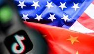 A photo taken on April 10, 2025 shows the Chinese social networking service TikTok's logo on a smartphone screen and US' and China flags combo illustration on a laptop screen in Frankfurt am Main, western Germany. (Photo by Kirill Kudryavtsev / AFP)
