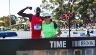 Australia's Gout Gout (L) and his coach Di Sheppard pose with his time of 19.84 as he celebrates winning the men's 200m final during the Australian Athletics Championships in Perth on April 13, 2025. (Photo by COLIN MURTY / AFP)