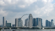 This photo shows the Singapore Flyer observation wheel (C) backdropped with the city skyline in Singapore on June 27, 2025. (Photo by Roslan RAHMAN / AFP)

