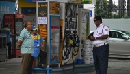 A traffic police personnel and a fuel attendant stand near a notice announcing the ban on refuelling petrol cars older than 15 years and diesel vehicles older than 10 years, displayed at a gas station in New Delhi on July 1, 2025. Photo by Arun SANKAR / AFP