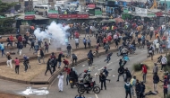 Protesters react amid clouds of tear gas fired by Kenya police officers during clashes at Saba Saba Day demonstrations in Nairobi on July 7, 2025. (Photo by SIMON MAINA / AFP)