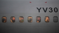 Venezuelan migrants who were jailed in El Salvador look out the windows of the plane as it lands at Simon Bolivar International Airport in Maiquetia, Venezuela on July 18, 2025. (Photo by Federico PARRA / AFP)