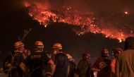 Firefighters attempt to extinguish a wildfire as smoke and flames rise from a forested area in the Gursu district of Bursa early on July 27, 2025. (Photo by ONUR YURTSEVER / AFP)