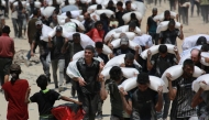 Palestinian walk carrying sacks of flour near Jabalia, in the northern Gaza Strip, on July 27, 2025, after planes dropped aid into Gaza. Photo by BASHAR TALEB / AFP