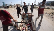 Palestinians transport a man, wounded as he waited for humanitarian aid at a GHF aid distribution point, at the entrance of the Bureij refugee camp in the central Gaza Strip on July 30, 2025. (Photo by Eyad BABA / AFP)