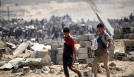 Palestinians return with bags from a food distribution point run by the US and Israeli-backed Gaza Humanitarian Foundation (GHF) group, near the Netsarim corridor in the central Gaza Strip on August 3, 2025. Photo by Eyad BABA / AFP