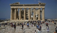 File: Tourists walk in front of the Parthenon Temple as they visit the Acropolis archaeological site in Athens on June 14, 2023. (Photo by Louisa Gouliamaki / AFP)
 
