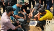 Mourners sit around the grave of Al Jazeera correspondent Anas al-Sharif, who was killed alongside other journalists in an overnight Israeli strike on their tent in Gaza City, following his burial at the Sheikh Radwan cemetery in Gaza City on August 11, 2025. (Photo by Omar Al-Qattaa / AFP)