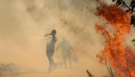 People use buckets of water to extinguish a wildfire that threatens their house in the Portuguese village of Antas, in Trancoso, on August 15, 2025. (Photo by Patricia De Melo Moreira / AFP)