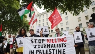 Protesters hold banners and Palestinian flags during a vigil for journalists killed in Gaza outside 10 Downing Street in central London on August 27, 2025. (Photo by Toby Shepheard / AFP)