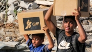 Boys walk with boxes of humanitarian aid they received at a distribution centre run by the US and Israeli-backed Gaza Humanitarian Foundation (GHF), as they cross the so-called 