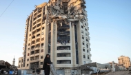 A Palestinian woman walks past a heavily damaged building in Gaza City on August 29, 2025. (Photo by Bashar Taleb / AFP)