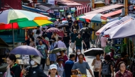 People walk past stalls at a street market in Seoul on September 3, 2025. (Photo by ANTHONY WALLACE / AFP)
