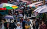 People walk past stalls at a street market in Seoul on September 3, 2025. (Photo by ANTHONY WALLACE / AFP)
