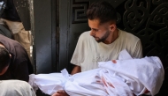 A Palestinian man carries the shrouded body of a child killed in Israeli strikes on Gaza City at dawn, during a funeral procession outside the Al-Shifa hospital on September 4, 2025, amid the war between Israel and the Hamas militant movement. (Photo by Omar AL-QATTAA / AFP)
