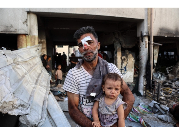 An injured man carries a toddler as others search for their belongings amid the rubble, in the al-Farabi school turned shelter for displaced Palestinians, after it was hit by an Israeli strike, in Gaza City in the northern Gaza Strip on September 7, 2025. (Photo by Omar AL-QATTAA / AFP)