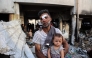 An injured man carries a toddler as others search for their belongings amid the rubble, in the al-Farabi school turned shelter for displaced Palestinians, after it was hit by an Israeli strike, in Gaza City in the northern Gaza Strip on September 7, 2025. (Photo by Omar AL-QATTAA / AFP)