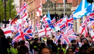 Supporters of British far-right activist Tommy Robinson whose real name is Stephen Yaxley-Lennon, walk through central London waving flags during a 'Free speech' march, on September 13, 2025. (Photo by CARLOS JASSO / AFP)