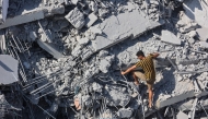 A Palestinian youth climbs the rubble of al-Ghafari tower after its destruction by Israeli airstrikes in Gaza City on September 15, 2025. Photo by Omar AL-QATTAA / AFP