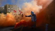A protester lights flares in Marseille, southeastern France, on September 18, 2025, during a day of nationwide strikes and protests called by unions over France's national budget. (Photo by Miguel Medina / AFP)