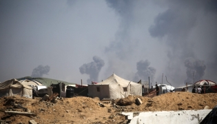 Tents of displaced Palestinians stand in the Nuseirat refugee camp in the central Gaza Strip, as plumes of smoke rise during Israeli bombardment above Gaza City, on September 19, 2025. (Photo by Eyad BABA / AFP)
