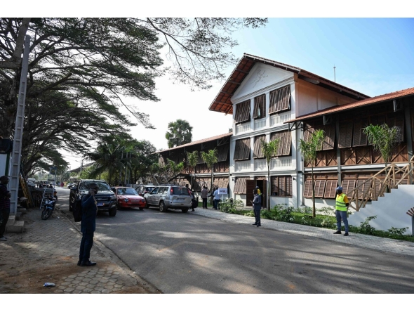 A view of people standing in front of the contemporary arts museum called the House of Art, a former post office and customs building, a remnant of the colonial era, of the Societe General Cote d'Ivoire (SGBCI) foundation in Grand-Bassam, a city listed as a UNESCO World Heritage Site, on September 25, 2025. (Photo by Sia KAMBOU / AFP)