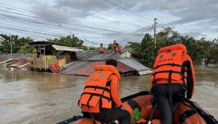 This handout photo taken on September 26, 2025 and released on September 27 by the Philippine Coast Guard shows coast guard personnel rescuing residents from their flooded house at the height of Severe Tropical Storm Bualoi, at a village in Ormoc City, Leyte province. (Photo by Handout / Philippine Coast Guard (PCG) / AFP)